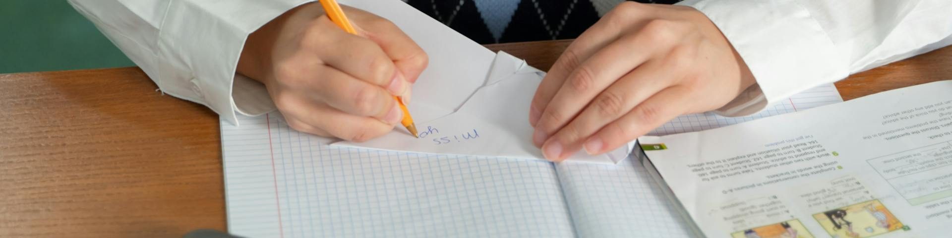 A focused university student sitting at a clean desk with books and a laptop, using flashcards for revision.