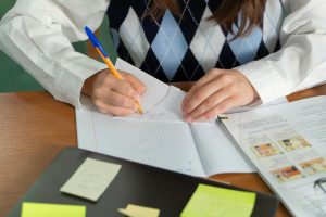 A focused university student sitting at a clean desk with books and a laptop, using flashcards for revision.